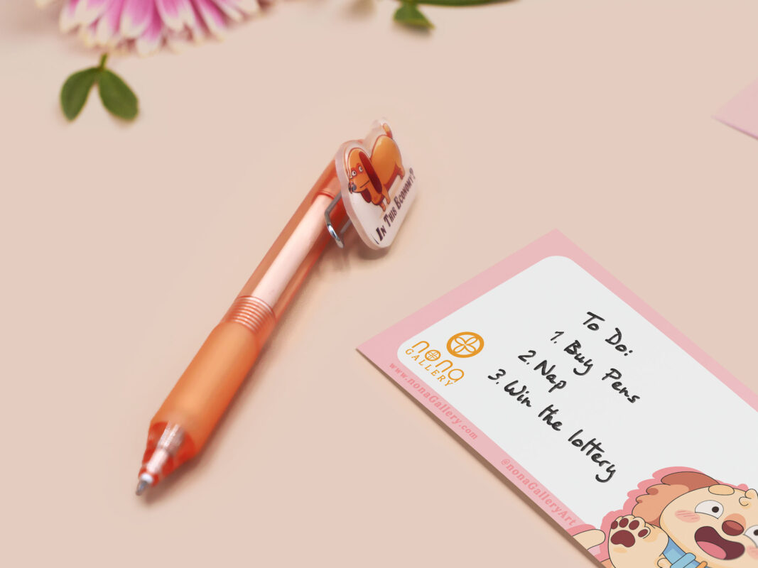 Orange ballpoint pen with black ink and a cute chibi dachshund sausage dog design.