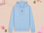 A blue long sleeve hoodie, with an embroidered chibi shrimp looking concerned and the quote Not so shrimple is it?