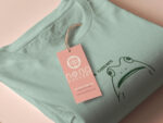 An embroidered green t-shirt design of a funny cartoon frog with the text a concern.