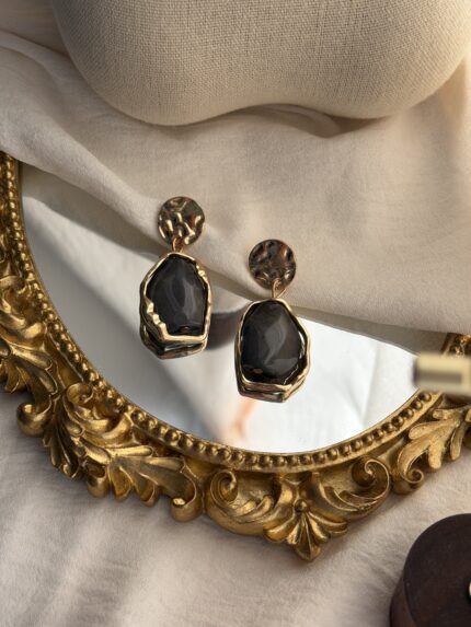 Elegant earrings on ornate mirror